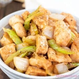 A square image showing a bowl of tender wok fried marinated chicken with celery, onions, and black pepper sauce.