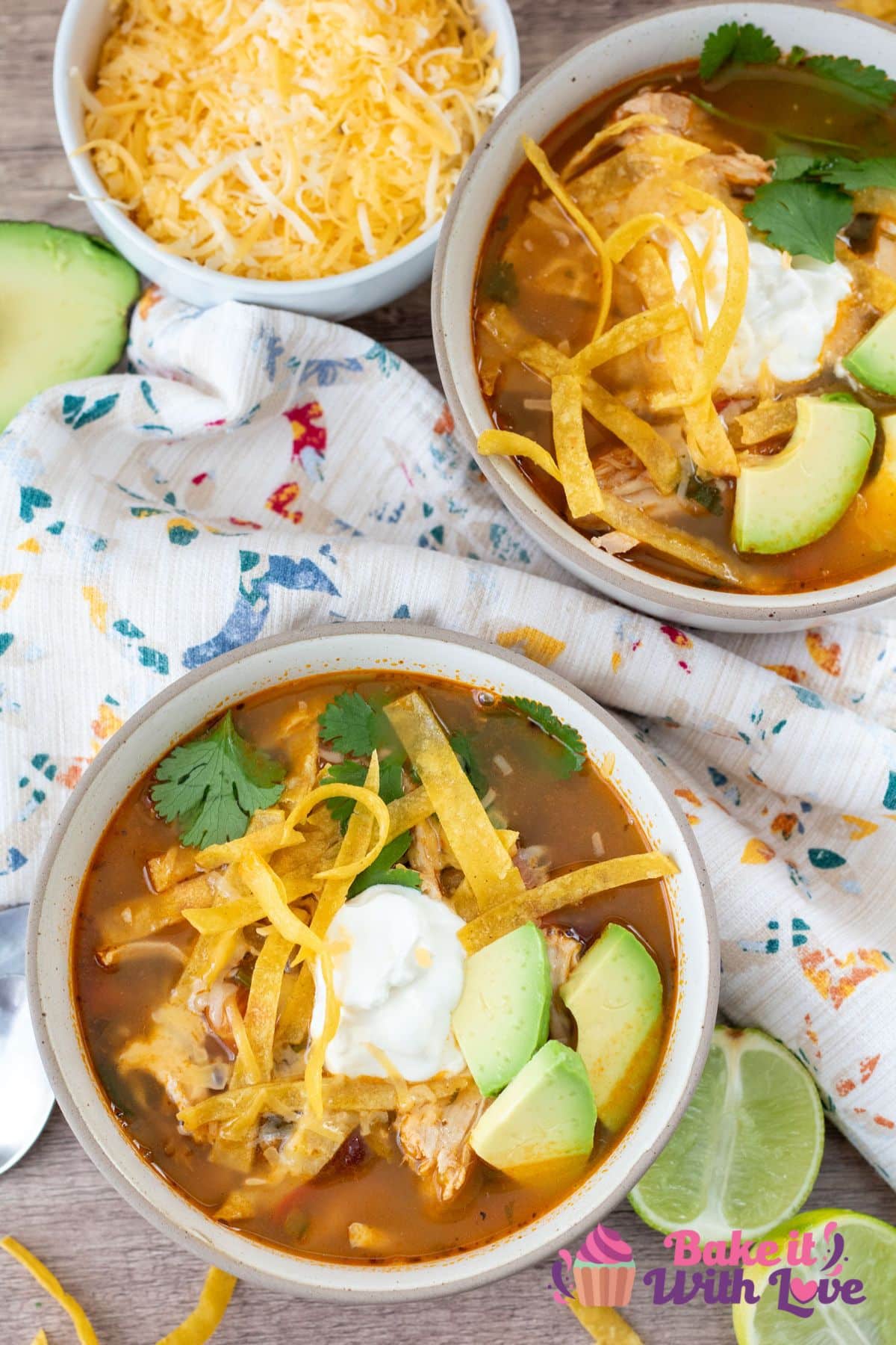 Best chicken tortilla soup recipe with two bowls dished up on a light wooden background with lime and tortilla strips around them.