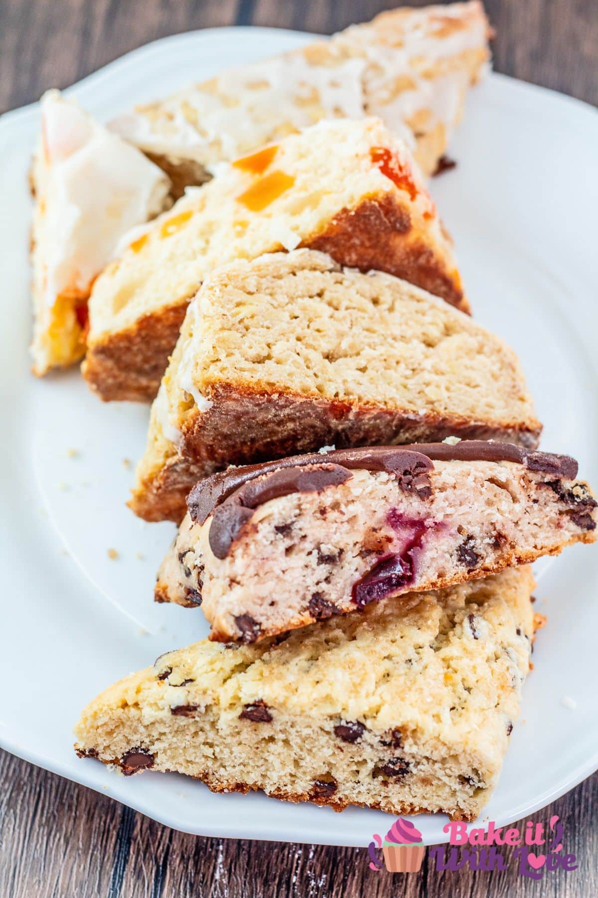 Master scones recipe baked into 5 delicious flavors and halved to show the tender crumb, set facing open side up on a white plate.