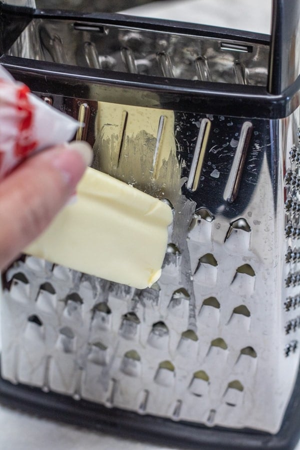 Box grater with a frozen stick of butter being grated on it.