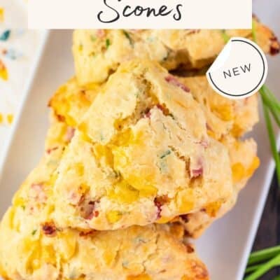 Ham, Cheddar, & Chives Scones recipe Pinterest pin hsowing an overhead shot of golden wedfe-shaped scones spotted with diced ham on a rectangular white serving platter.