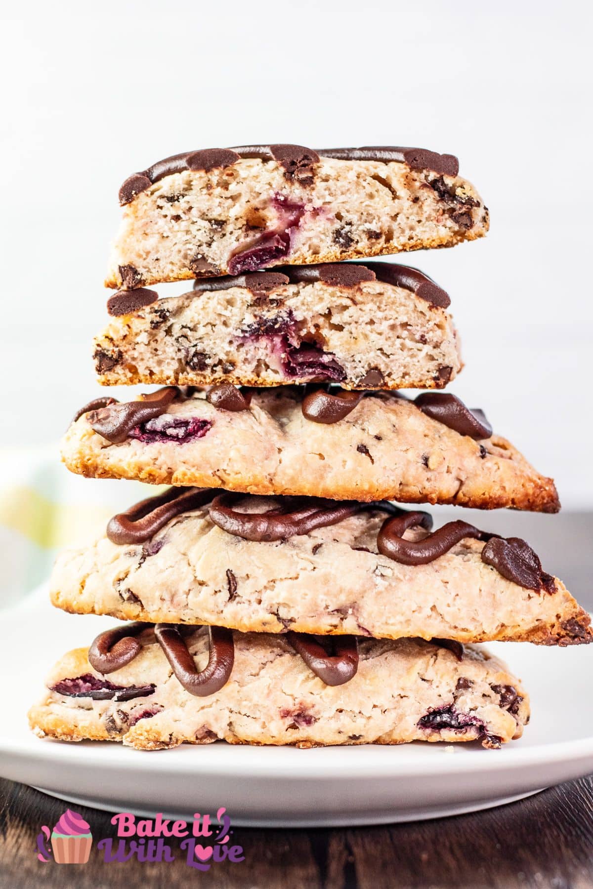 Best easy-to-make cherry chocolate chip scones recipe showing the stacked scones on a white plate with a cut scone on top with the cut side facing the camera to show the texture.