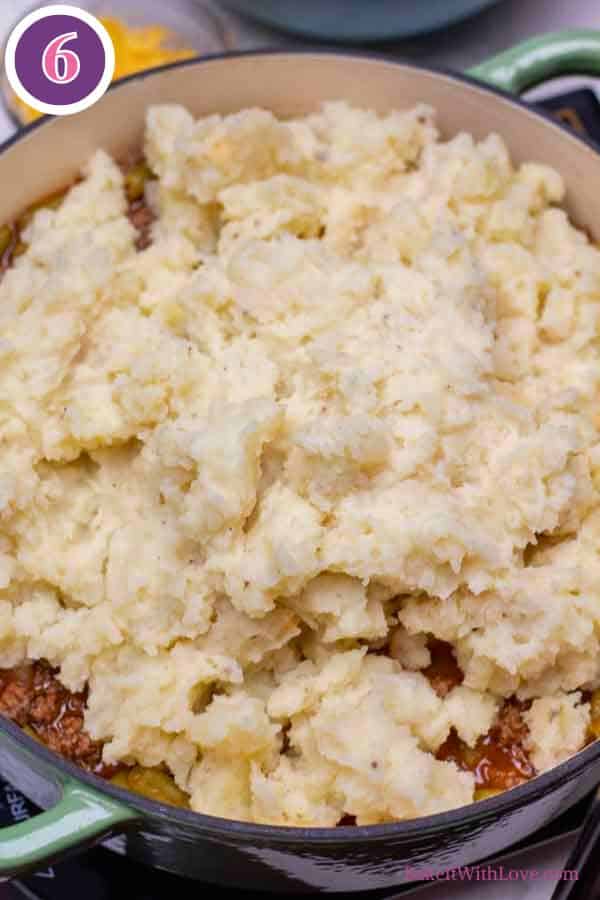 Hamburger pie casserole process photo 6 showing mashed potatoes spooned on top of the beef, onion, green bean mixture in the casserole dish.