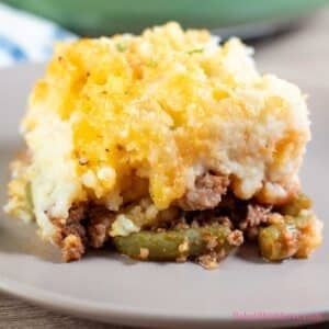 A square serving cut out from the hamburger pie casserole and plated on a a light tan plate.