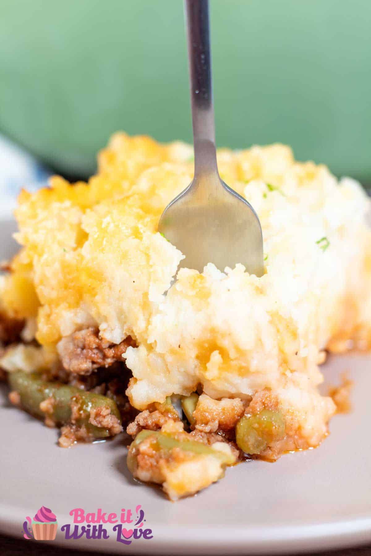 Homemade hamburger pie casserole dished up and being forked for a bite.