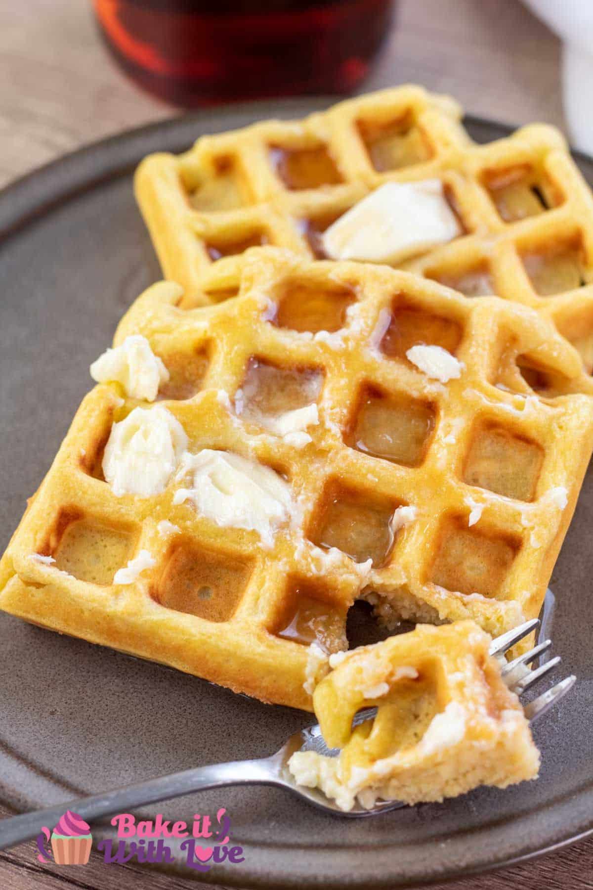 Tall image showing homemade waffles with maple syrup on a plate.