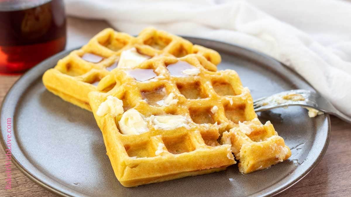 Wide image showing homemade waffles with maple syrup on a plate.